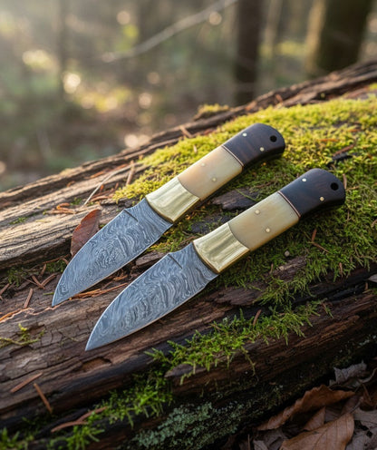 SUSA KNIVES 2-piece handmade damascus steel skinner knife set with wood and bone handles on a mossy log.