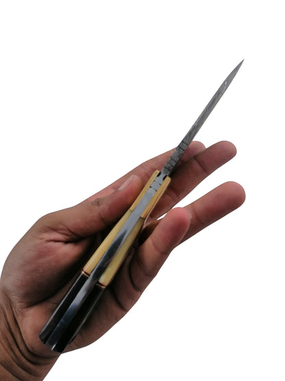 SUSA KNIVES handmade damascus steel skinner knife with a two-tone handle held in a hand, side profile view.
